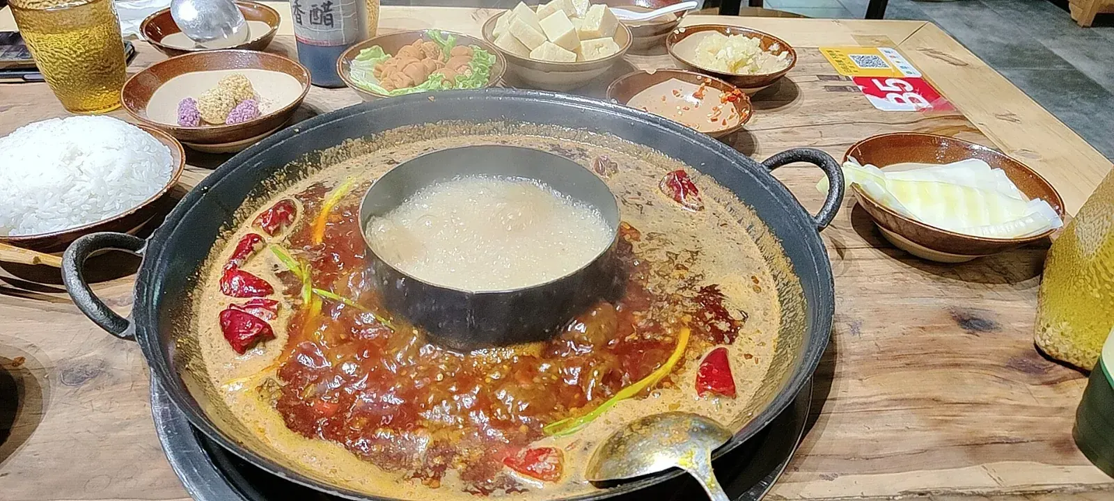 A divided Sichuan hotpot with chilies, aromatics and a mild broth